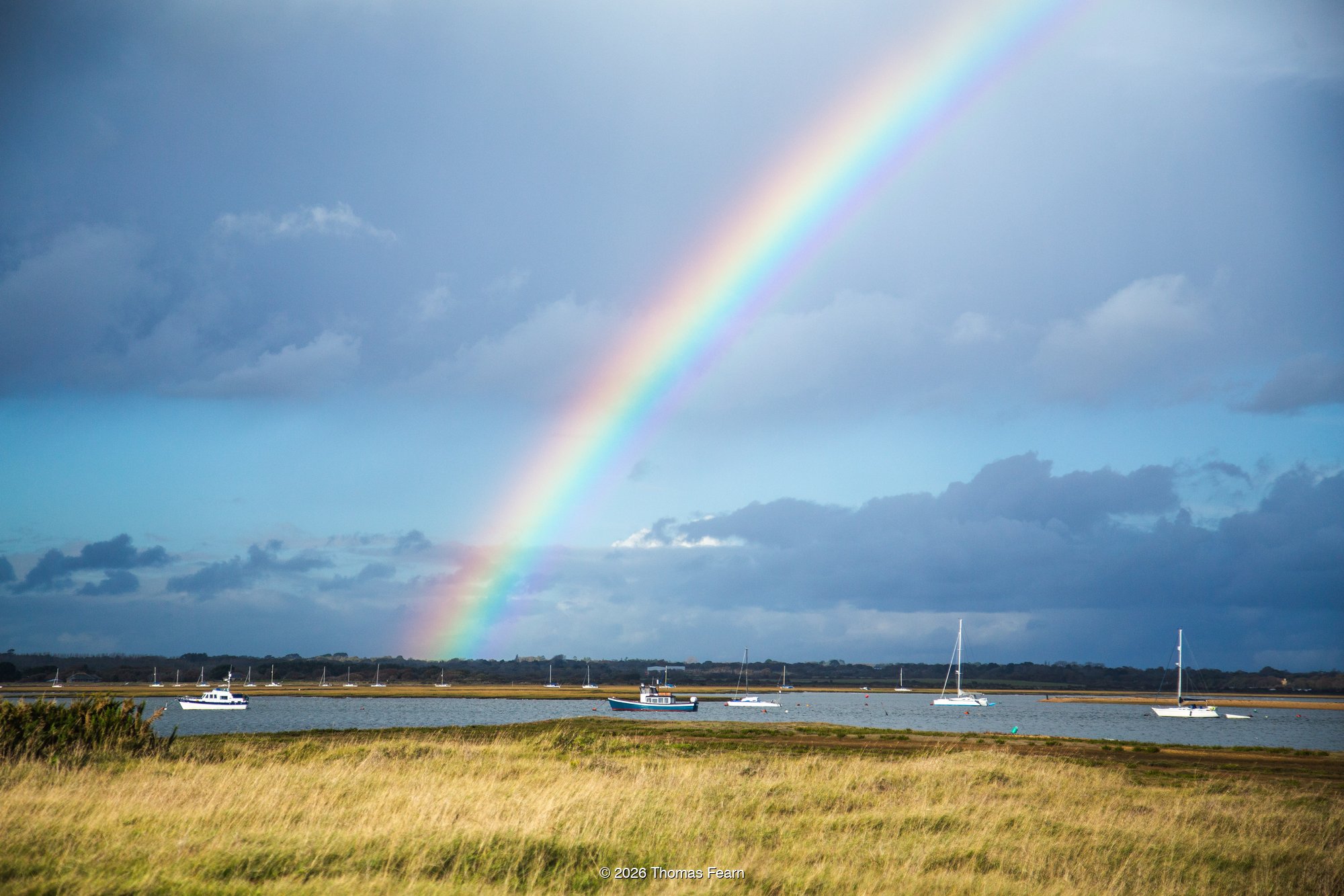 Rainbow Over a Coastal Estuary with Moored Boats